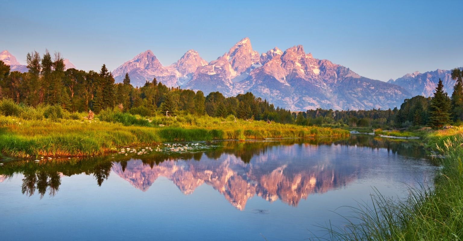 Mountain range reflected in a river valley at sunrise